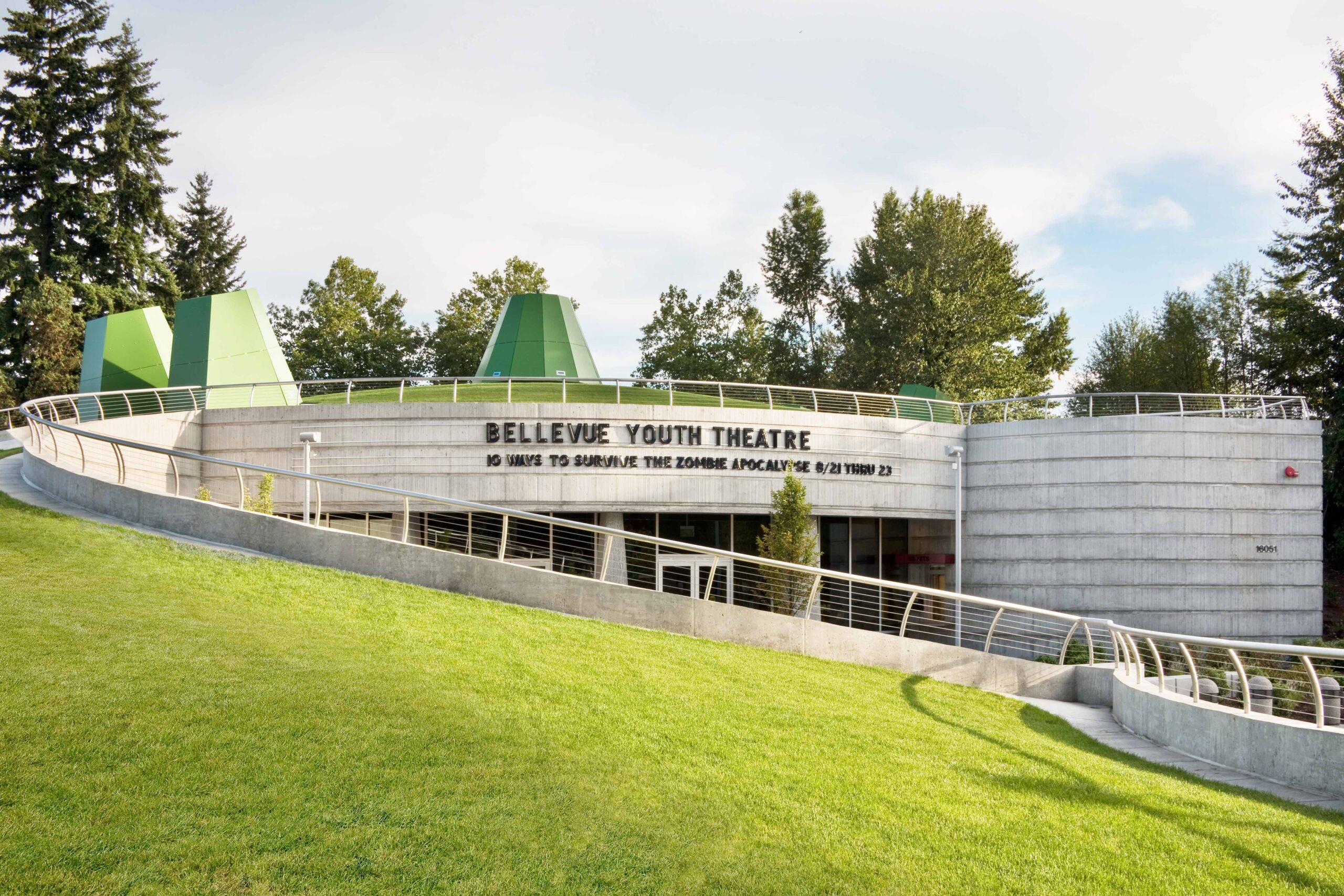 The main terminal building of King County International Airport (Boeing Field) in Seattle, WA, featuring a red brick façade, arched windows, a clock, and an American flag flying above against a clear blue sky.