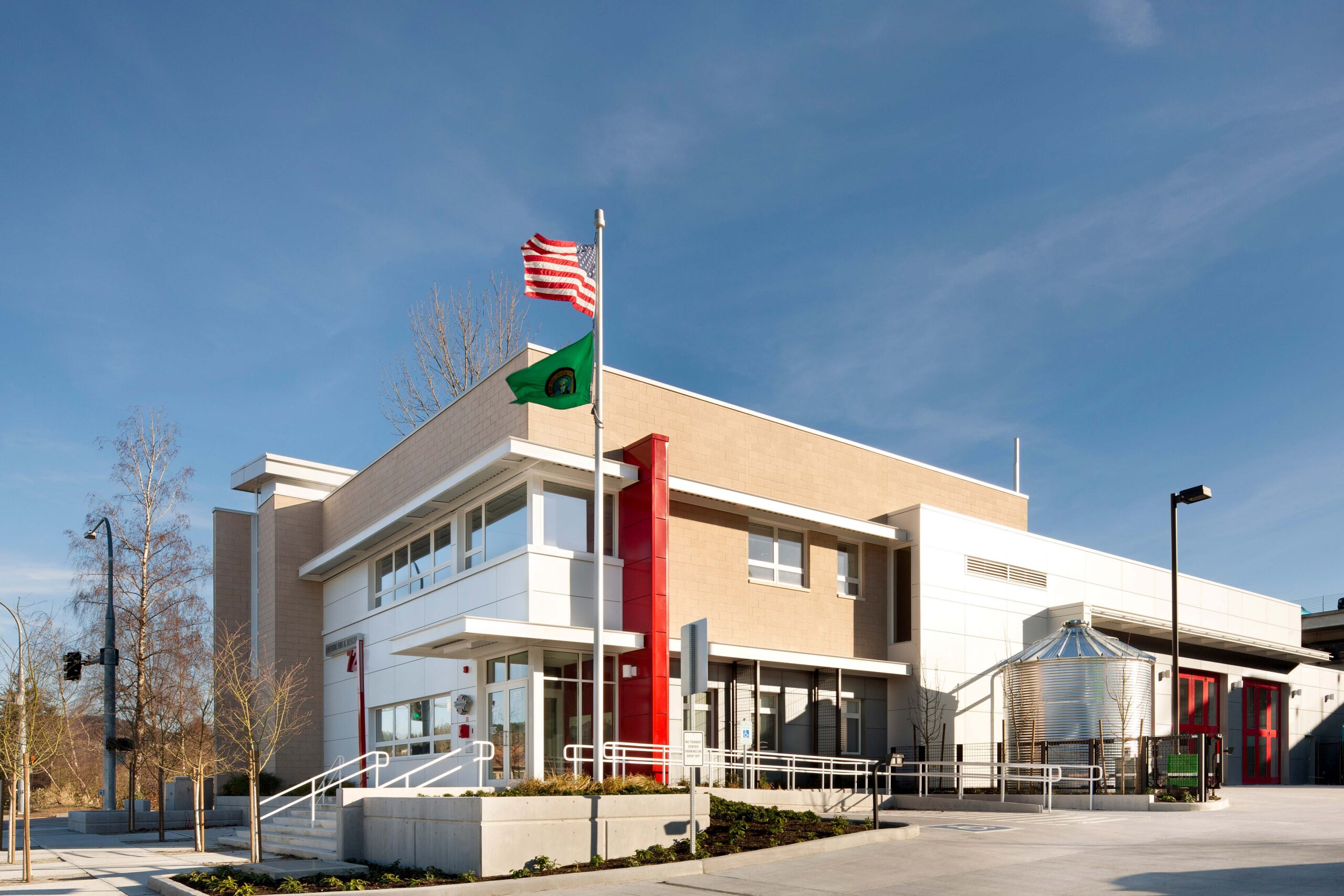HopeWorks Station, a modern mixed-use building in Seattle, WA, featuring retail spaces on the ground floor and residential units above. The façade includes textured siding, operable window shades, and a rooftop terrace.