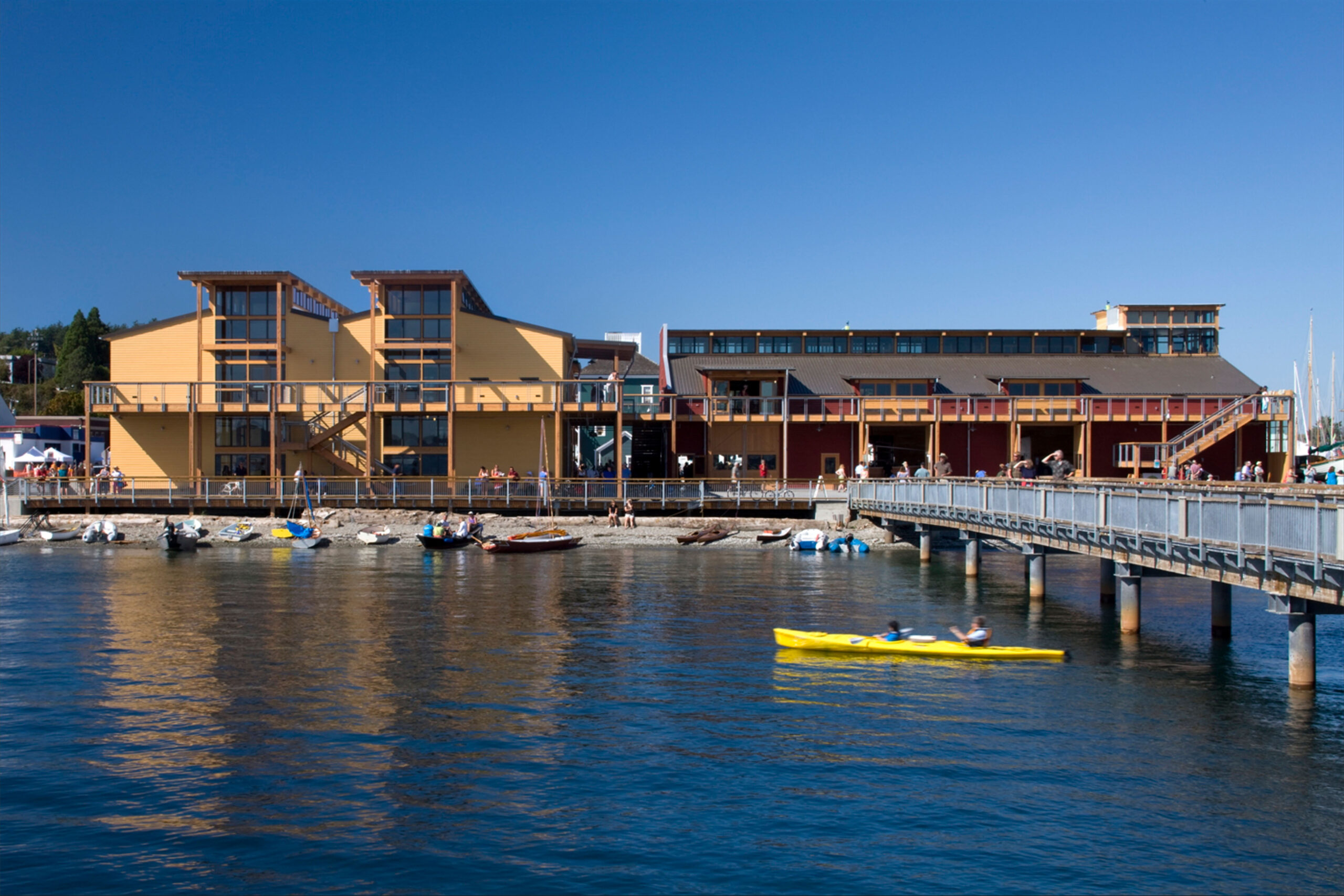HopeWorks Station, a modern mixed-use building in Seattle, WA, featuring retail spaces on the ground floor and residential units above. The façade includes textured siding, operable window shades, and a rooftop terrace.