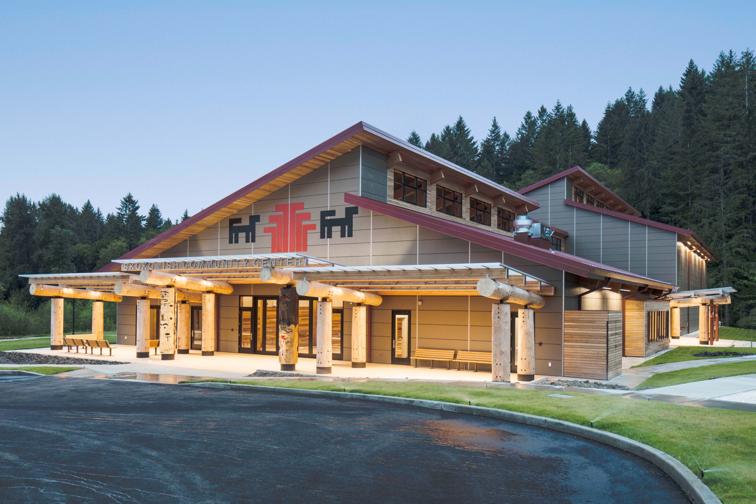 The main terminal building of King County International Airport (Boeing Field) in Seattle, WA, featuring a red brick façade, arched windows, a clock, and an American flag flying above against a clear blue sky.