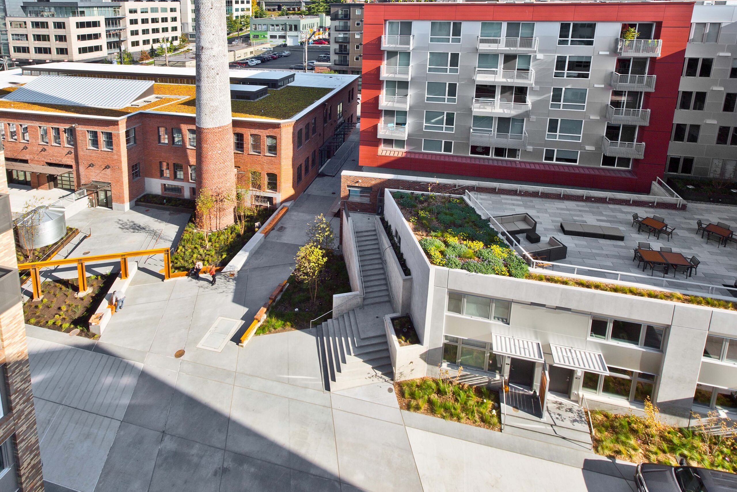 HopeWorks Station, a modern mixed-use building in Seattle, WA, featuring retail spaces on the ground floor and residential units above. The façade includes textured siding, operable window shades, and a rooftop terrace.